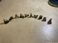 Overview photo showing all 10 small ceramic figurines in a row on a flat surface.