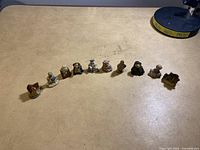 Wide shot of all 10 small figurines arranged in a row on a wooden surface