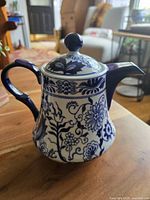 Frontal view of the cobalt blue and white floral teapot with lid, showing curved handle and floral pattern.