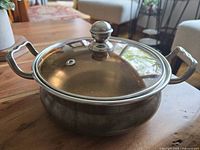 Side angle showing copper saucepan body, double handles, and lid with knob.