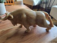 Left side view of carved onyx bull figurine showing natural color bands and muscular shape.