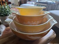 Stacked set of four PYREX Cinderella bowls with yellow exterior and white floral pattern