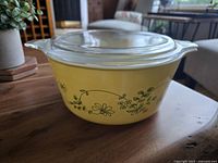 Clear glass lid on top of a yellow Pyrex casserole dish with green floral Shenandoah pattern on the exterior.