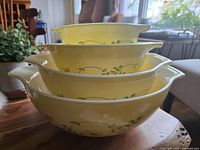 Side view of stacked Pyrex Shenandoah Cinderella bowls showing yellow floral botanical pattern and nested sizes