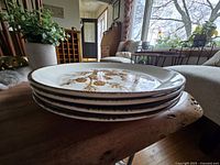 Side view of four stacked vintage stoneware plates showing thickness and edge detail.