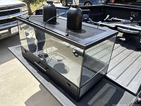 Photo of 50-gallon glass aquarium tank with black frame and hood on truck bed, showing lighting fixtures on top.