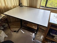 Front and angled view of the drafting table showing the large rectangular surface and black metal legs.