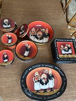 Overview of the dinnerware set showing stacked square plates, large bowls, and multiple small bowls and plates, all with cartoon chef illustrations and vibrant colors.