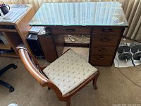 Full view of desk with a glass top showing wood frame, shelves underneath, and the chair in use.
