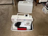 Singer 9410 sewing machine on carpet, showing entire sewing machine in carrying case with accessories included inside base.
