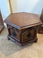 Full view of hexagonal wooden table showing its shape, brown wood finish, carved raised edges, and feet.