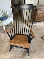 Full view of Windsor chair showing natural wood seat and arms with black painted spindles and stenciled backrest design.
