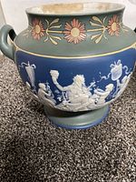 Front side showing Bacchus with merchildren cameo scene on blue band, with floral green ceramic top and handles.