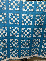 Front side of the quilt showing the blue and white patterned blocks creating floral star shapes in good condition.