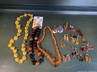 Overview of three necklaces and multiple earring pairs displayed on green background