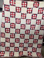 Front side of the quilt showing red and white patchwork squares with floral designs in a checkerboard pattern