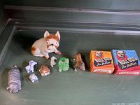 Photo showing an assortment of bulldog figurines including ceramic, glass, and porcelain, plus two vintage Bulldog Jan Kellers boxes.