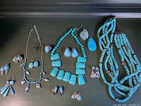 Wide view of entire turquoise jewelry lot on dark surface