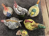 Top view of five ceramic animal-shaped teapots showing rooster, duck, and hen shapes with colorful painted details