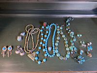 All necklaces, earrings and rings arranged on dark surface