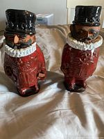 Two vintage ceramic Chelsea Pottery Beef Eater figurines standing side by side on a cloth surface, showing front and side views