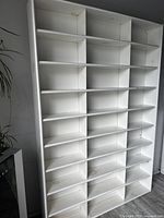 Front angled view of white shelving unit showing all 27 compartments evenly spaced for hair colour tube storage. Minor wear visible on surfaces.