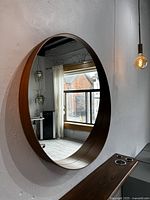 Large round wood-framed mirror mounted on the wall