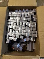 Top-down view of an open cardboard box filled with numerous unopened Wella Illumina hair colour boxes