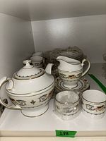 Wide view of teapot, creamer, sugar bowl, cups and stacked plates on shelf