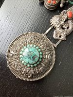 Close-up of round engraved medallion belt link with central turquoise cabochon and beaded border