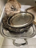 Top view of stacked silver plated trays with wrapping paper and handles visible.