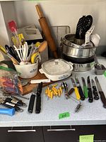 Overview of most kitchen utensils including wooden spoons, rolling pins, spatulas, knives, can openers, cookie cutters, bottle openers, and a CorningWare baking dish