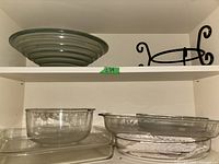 Shelf with multiple clear glass baking trays and round bowls, bottom shelf.