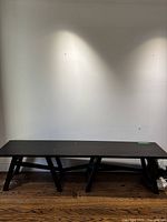 Photo showing full view of the rectangular dark wood bench against a wall on wood flooring.