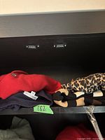 Folded cashmere sweaters (red, striped, leopard print, black) arranged on black shelf