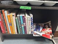 Books and magazines shelf containing Jamie Oliver cooking books and assorted cooking-themed books and magazines.