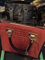 Front view of red croc-embossed tote with braided handle and decorative hardware