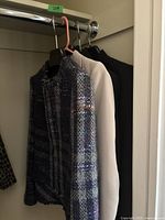 Three jackets hanging on a closet rod—Burberry tweed, Claude Zana beige, and black blazer visible