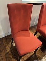 Front view of a red microfiber dining chair showing seat and high back on wood floor.