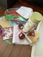 Photo showing assorted gift wrap sheets, white tissue paper, gift bag with circular pattern, two rolls of curling ribbon, and some gift tissue sheets.