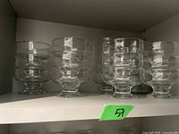 Set of eight clear glass dessert dishes on a shelf, showing their shape and arrangement.