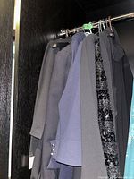 Photo showing six women's jackets on hangers in a closet with various shades such as black, grey, navy, and textured fabric details.