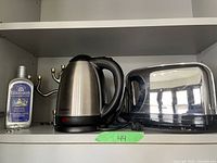 Photo shows a Chefman electric kettle, Goddard's silver polish bottle, the Jacob Rosenthal silver Menorah, and partially visible Philips toaster on a shelf.