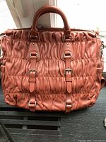 Front view of coral-orange ruched tote bag showing overall design and condition