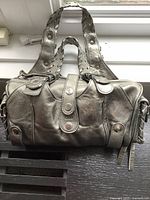 Front view of barrel-shaped handbag showing braided handles and front snap strap