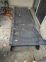 View of one lounge chair on patio showing mesh sling seat and metal frame