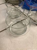 Photo of two clear glass vases, one with a curved top edge and one with an inward curved lip, both transparent and round-shaped.