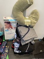 Photo showing stacked sleepwear items, the boxed SoftHeat heating pad, and a brown soft neck pillow.