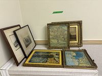 Overview of six framed artworks: two prints leaning at left and four small paintings arranged right and front
