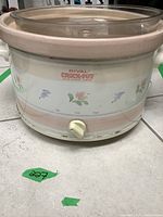 Front and partial side view of the Rival Crock-Pot slow cooker showing floral pattern and control knob with Off, Low, High settings.